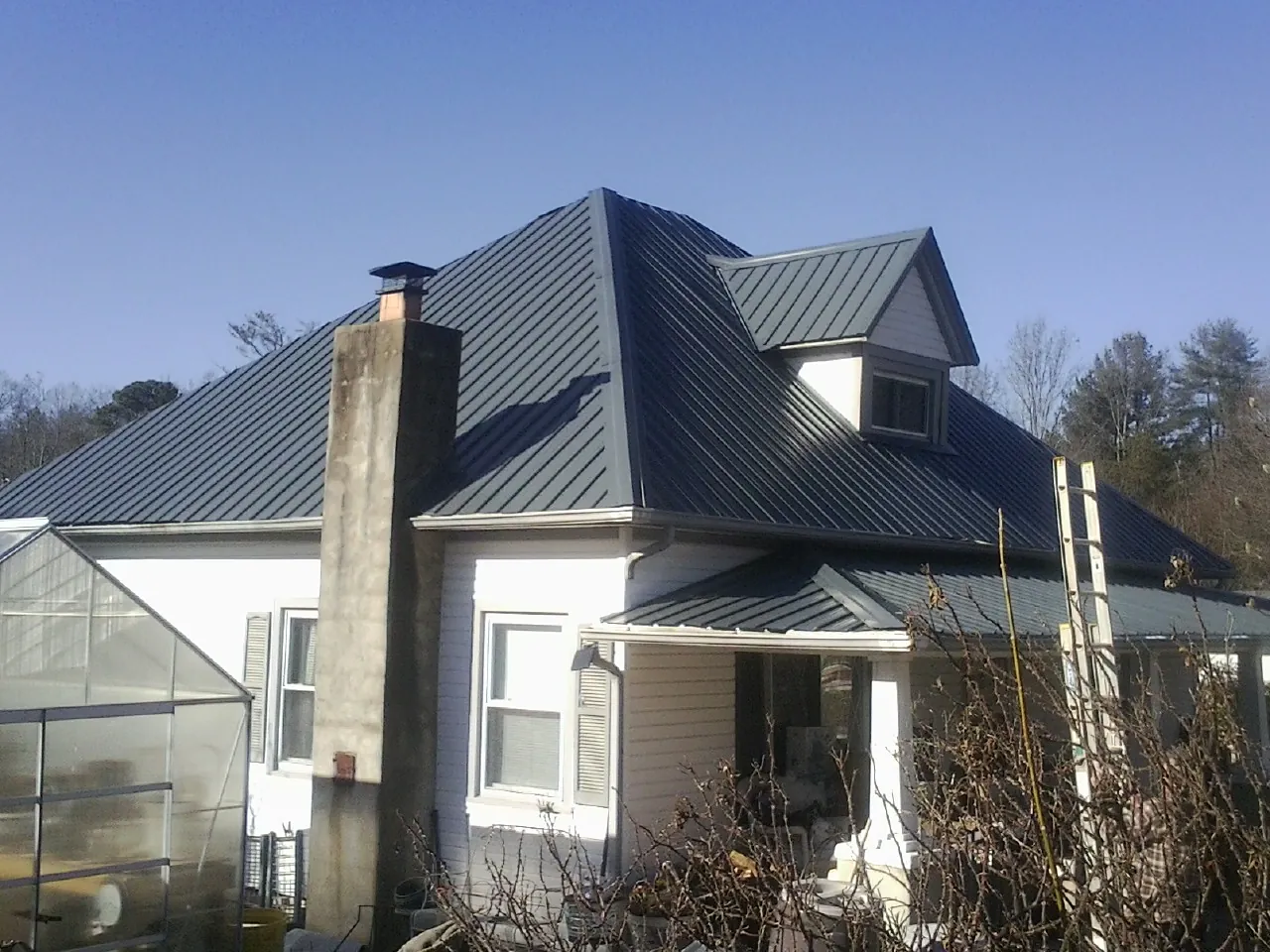 Dark blue standing seam metal roof on a white farmhouse with dormer — Slate & Tile Roof Repair by Roofing Brothers in Glassboro