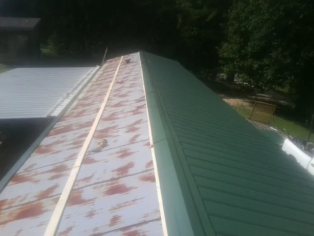 Old rusted panels beside newly installed green metal roofing — Wind Damage Roof Repair by Roofing Brothers in Glassboro