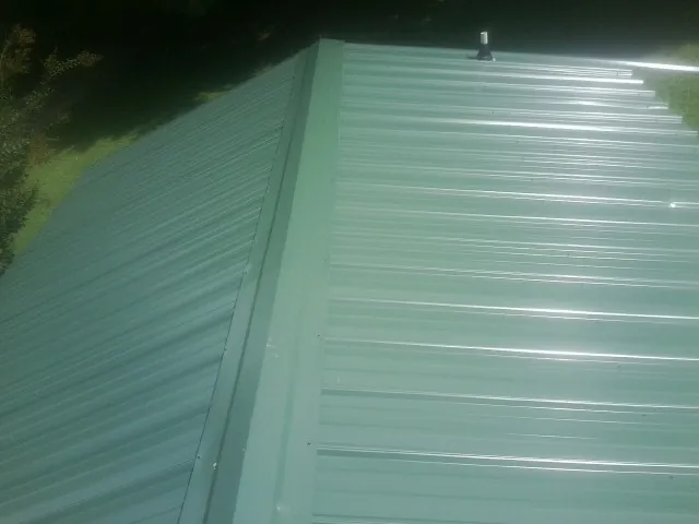 New green metal panels meeting at the ridge of a roof — Flat Roof Repair work by our crew in Glassboro