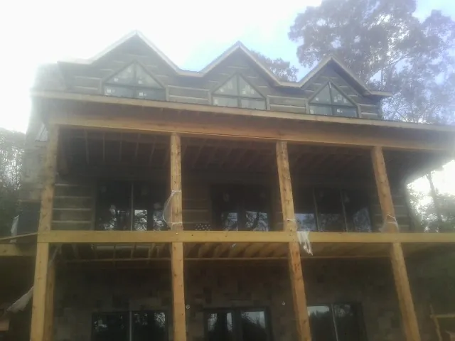 Dormers and porch framing on a large log home under construction — Roof Coating work by our crew in Glassboro