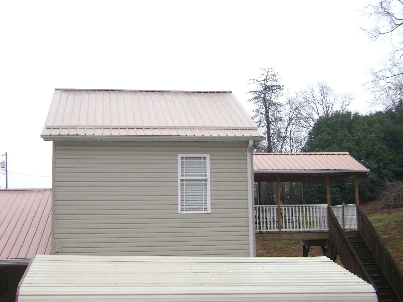 Tan metal roofs on a two story addition and attached porch, from a Roof Replacement job in Glassboro