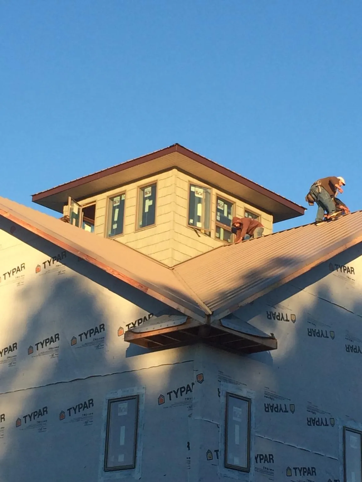 Roofers working around a rooftop cupola on a new metal roof at sunset — Roof Waterproofing in Glassboro by Roofing Brothers